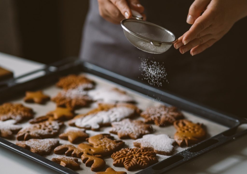 baker-sprinkles-icing-sugar-from-a-sieve-on-christmas-gingerbread-.jpg